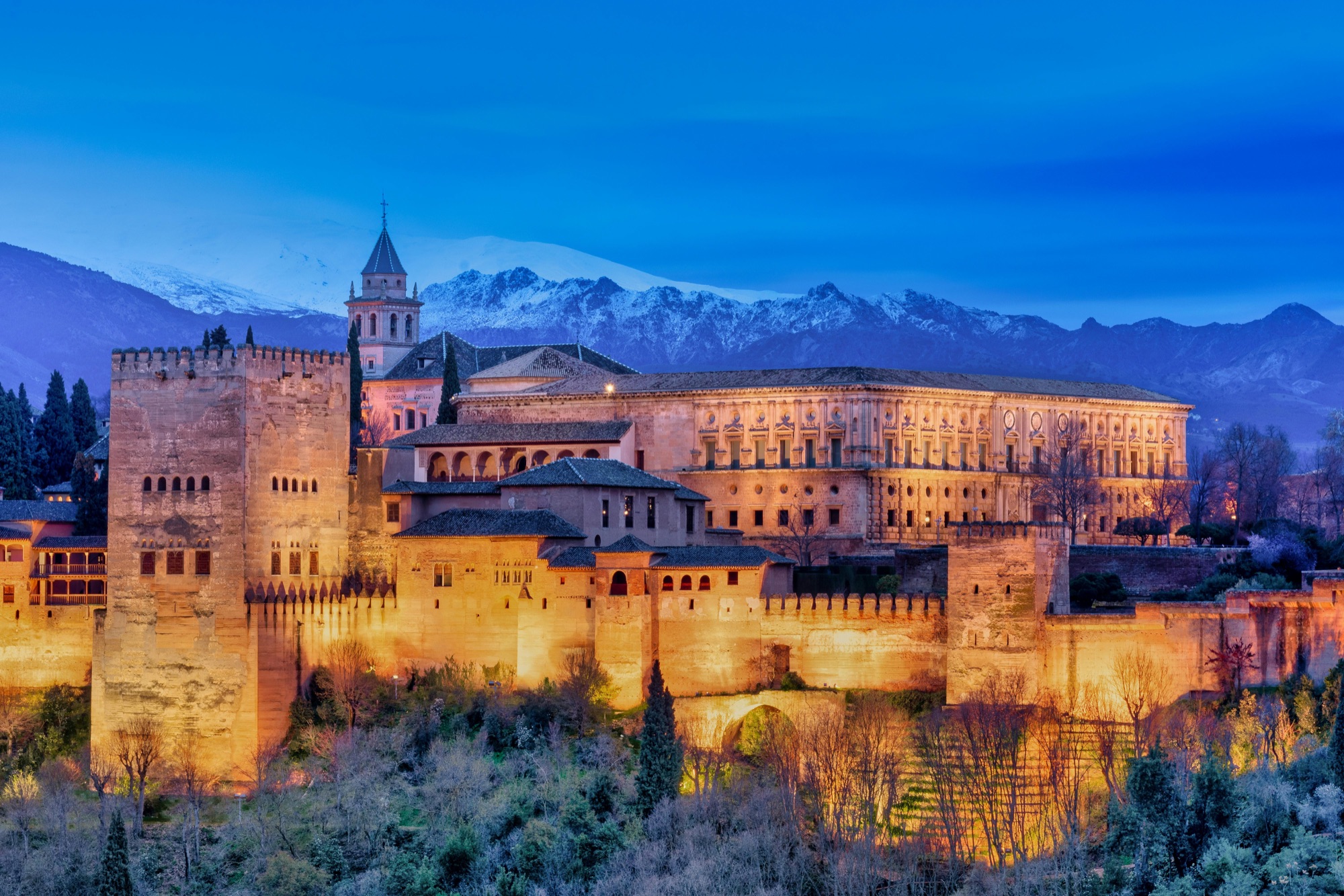The Alhambra lit at dusk with the snowy Sierra Nevada behind